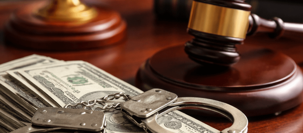 Criminal defense cost concept with gavel, handcuffs, and cash on desk