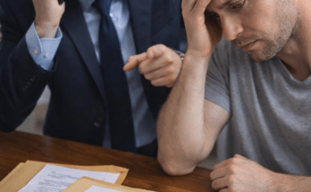 Debt collector angrily calling on phone while a worried consumer reviews legal debt documents at a desk, illustrating debt collection pressure and potential FDCPA violations.