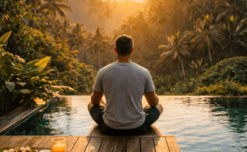 Man meditating by infinity pool at sunrise surrounded by tropical nature representing abundance mindset