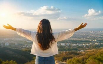 Person embracing an abundance mindset while overlooking a peaceful sunrise